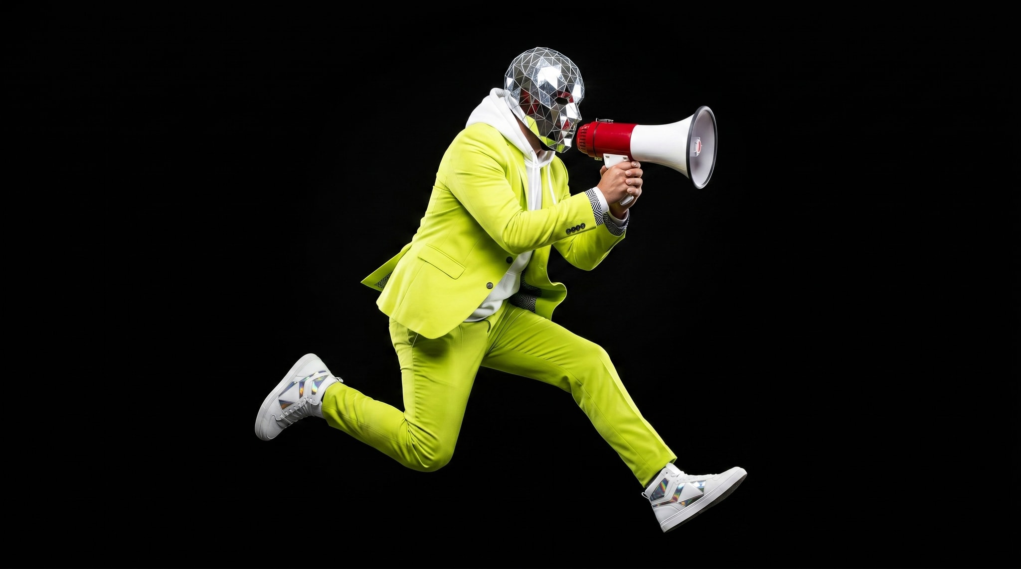 Man in lime pak met discobal-masker schreeuwt door een megafoon